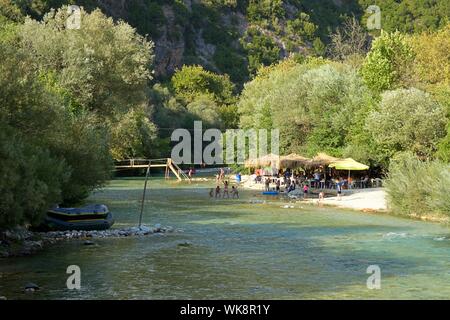 Kinder spielen am Ufer des Acheron Flusses bei Acheron Quellen in Glyki Dorf in Griechenland in der Sommersaison in der Nähe von Wasser Restaurant mit Familien. Stockfoto