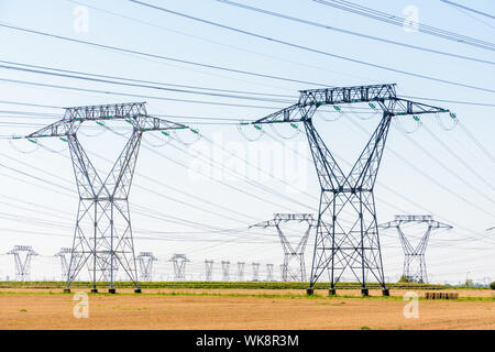 Dutzende von Strommasten in der französischen Landschaft unter einem klaren blauen Himmel. Stockfoto