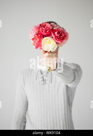 Junger Mann bedeckte sein Gesicht mit Blumenstrauß. Stockfoto