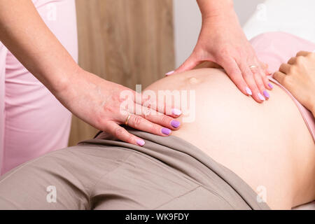 Nahaufnahme der Frauenarzt Frauenarzt untersucht manuell schwangeren Bauch pränatale Checkup durchführen Stockfoto