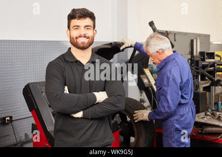 Junger Mann erfolgreich als Mechaniker oder Mechatronik Lehrling in der Werkstatt Stockfoto