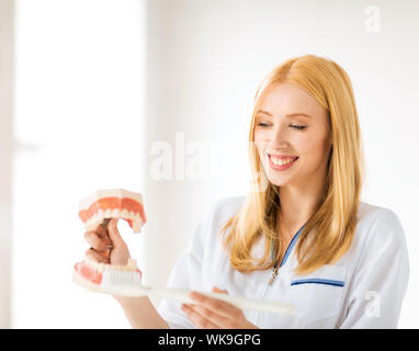 Ärztin mit großen Kiefer und Zahnbürste lächelnd... Stockfoto