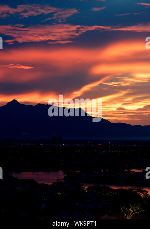 Brennende rote Himmel und Wolken über Guning Serapi Berge bei Sonnenuntergang in Kuching, Sarawak, Malaysia Stockfoto