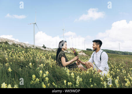 Ein Kerl gibt seiner Freundin Wiese Blumen. Romantik und Liebe. Stockfoto