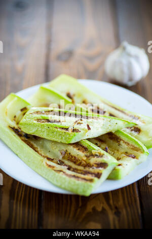 Gegrillte Zucchini mit Zwiebeln in einem Teller, auf einen Tisch. Stockfoto