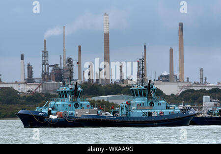 Fawley Marine, Southampton, England, UK. Apex und Phenix zwei Voith Traktor Schlepper mit Rolls-Royce-Triebwerken, neben Fawley Marine Raffinerie Stockfoto