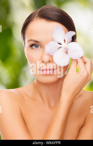 Gesundheit und Schönheit, Eco, bio, Natur Konzept - entspannte Frau mit orchideenblüte über Auge Stockfoto