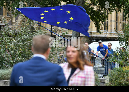 Eine EU-Flagge ist WINKTE als ehemalige Einwanderungsminister Caroline Nokes zu den Medien auf College Green außerhalb des Houses of Parliament in Westminster, London spricht. Stockfoto