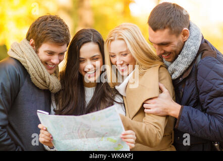 Urlaub und Tourismus-Konzept - Gruppe von Freunden oder Paare mit Touristenkarte im Herbst park Stockfoto