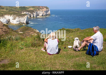 Ein paar und ihren Hund ruht auf den Klippen bei Flamborough Head, Yorkshire, Großbritannien Stockfoto