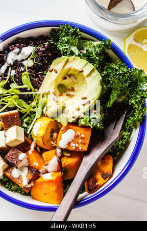 Buddha Schüssel Salat mit schwarzen Reis, Avocado, Tofu, Yam, Grünkohl und Tahini, weißen Hintergrund. Stockfoto