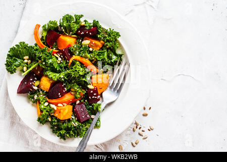 Kale Salat mit gebackenem süßen Kartoffeln, Karotten und Rüben in eine weiße Platte. Stockfoto