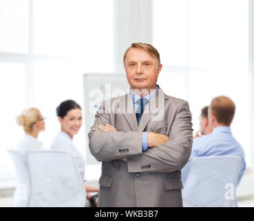 Geschäft, Büro und Bildung Konzept - schwere Buisnessman oder Lehrer in Anzug mit Team auf der Rückseite Stockfoto