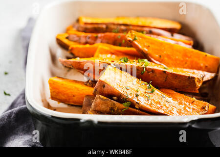 Gebackene süsse Kartoffel Scheiben mit Gewürzen in der auflaufform. Gesunde vegane Ernährung Konzept. Stockfoto