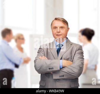 Geschäft, Büro und Bildung Konzept - schwere Buisnessman oder Lehrer in Anzug mit Team auf der Rückseite Stockfoto