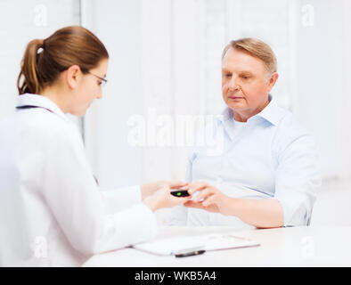Gesundheitswesen, ältere und medizinische Konzept - Ärztin oder Krankenschwester mit Patienten Blutzucker-Messwert Stockfoto
