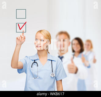 Gesundheitswesen, Medizin und Technik-Konzept - lächelnd junger Arzt oder Krankenschwester auf roten Häkchen im Kontrollkästchen Stockfoto
