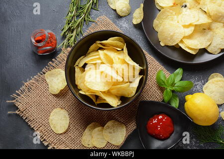 Schüssel mit knusprig hausgemachte Pommes Frites mit Ketchup, Rosmarin, Kräutern und Gewürzen auf dunklem Hintergrund serviert. Junk food Konzept Stockfoto