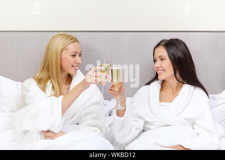 lächelnd Freundinnen mit Champagner Gläser im Bett Stockfoto