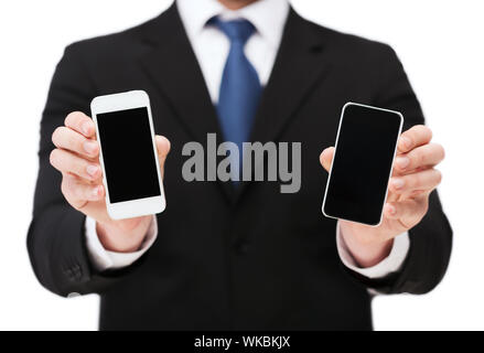 Business, Internet und Technologie-Konzept - Geschäftsmann zeigt zwei Smartphones mit leeren schwarzen Bildschirme Stockfoto