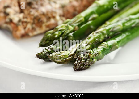 Frisch sautierte Spargel mit Lachs im Hintergrund. Extrem flache Tiefenschärfe mit selektiven Fokus auf Tipp von Spargel. Stockfoto