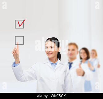 Gesundheitswesen, Medizin und Technik-Konzept - lächelnd Ärztin auf checkbox Stockfoto