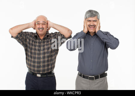 Zwei Männer mit Händen, die die Ohren bedecken Stockfoto