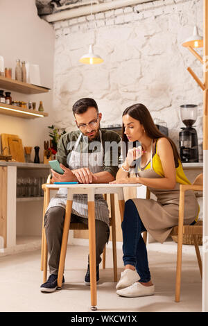 Diskussionen über neue Menü. Frau sitzt in der Nähe von Ehemann beim Besprechen neue Menü für ihre Cafeteria Stockfoto