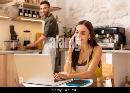 Frau Anrufe empfangen. Frau Empfangen von Anrufen von Kunden beim Sitzen am Laptop und in Familienunternehmen Stockfoto