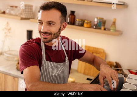 Spaß an der Arbeit. Dark-eyed barista Schürze tragen, seinen Arbeitstag sehr genießen. Stockfoto