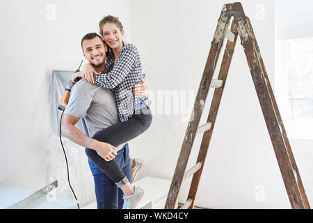 Amorous junges Paar mit Bohrer und Leiter während der Renovierung in neues Haus Stockfoto