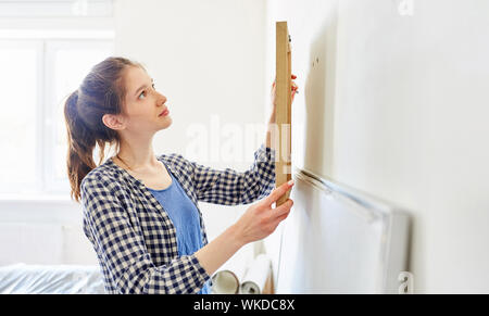 Junge Frau als Home Improvement hängen durch das Bild in Ihrem neuen Zuhause oder einer Ferienwohnung Stockfoto