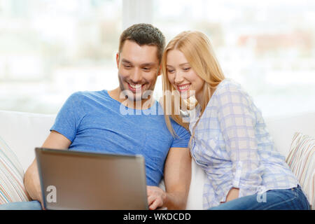 Liebe, Familie, Technologie, Internet und Glück Konzept - Lächeln glückliches Paar Witl Laptop-Computer zu Hause Stockfoto