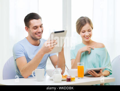 Nahrung, Wohnung, paar, Technologie-Konzept - lächelnde paar mit TabletPC lesen Nachrichten und frühstücken zu Hause Stockfoto