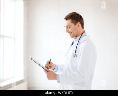 Gesundheitswesen und Medizinische Konzept - Lächeln männlicher Arzt mit Stethoskop und Zwischenablage im Krankenhaus Stockfoto