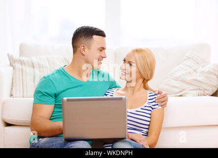 Liebe, Familie, Technologie, Internet und Glück Konzept - Lächeln glückliches Paar Witl Laptop-Computer zu Hause Stockfoto