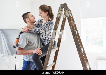 Verliebter junge Paar zusammen im neuen Haus renovieren mit Leiter Stockfoto