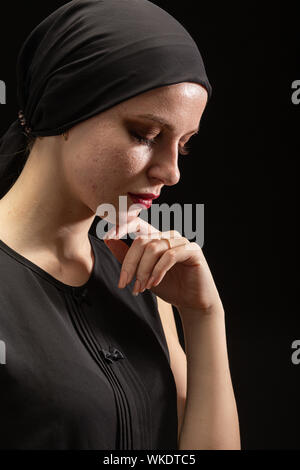 Junge traurige Frau mit pimply Haut auf schwarzem Hintergrund unten schauend, Seitenansicht Stockfoto