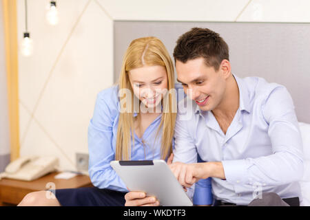 Business, hotel, Trave und Technologie Konzept - lächelndes Paar mit Tablet-PC Computer im Hotel Zimmer Stockfoto