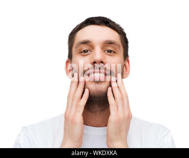 Gesundheit und Schönheit Konzept - Schöne lächelnden Mann sein Gesicht berühren Stockfoto