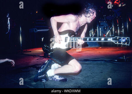 Angus Young von AC/DC-Gitarre spielt auf seinen Knien auf der Bühne im Palladium Theater in New York City im Juni 1979. Es ist eine Hand sichtbar auf der linken Seite. Stockfoto