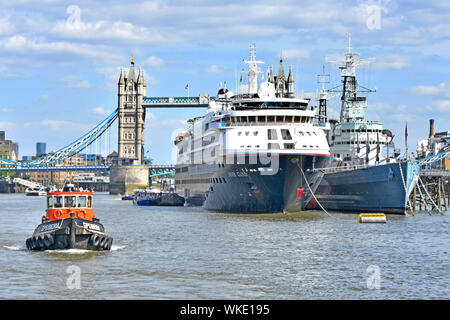 Themse Tug Boat Pässe Kreuzfahrtschiff liner Silver Cloud neben Kriegsschiff HMS Belfast Imperial War Museum mit iconic Tower Bridge London UK angedockt Stockfoto