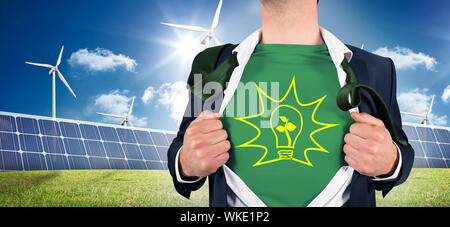 Geschäftsmann öffnung Shirt in Superhelden Stil gegen große Solarpanel und Drei Windkraftanlagen Stockfoto