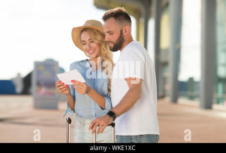 Glückliches Paar an der Bordkarte Kontrolle Abfahrtszeit suchen Stockfoto