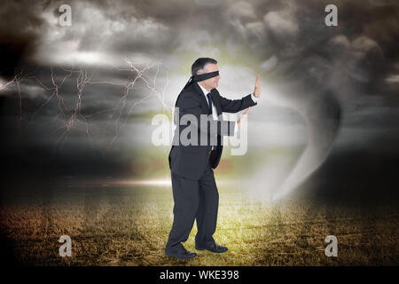 Reife Kaufmann in eine Augenbinde gegen stürmischen Himmel mit Tornado über auf dem Feld Stockfoto