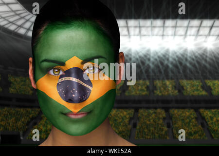 Das zusammengesetzte Bild im schönen Brasil in Gesicht Farbe gegen große Fußball-Stadion mit Fans in Gelb Stockfoto