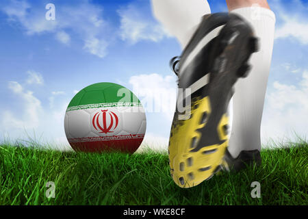 Das zusammengesetzte Bild im Fußballschuh kicking Iran Kugel gegen Bereich der Gras unter blauen Himmel Stockfoto