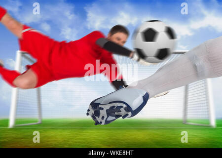 Das zusammengesetzte Bild von Fußballspielern Bekämpfung für den Ball gegen Fußballplatz und Ziel unter blauem Himmel Stockfoto