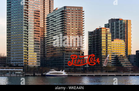 NEW YORK CITY/USA - Januar 26, 2018: Wahrzeichen Pepsi Cola Schild in Long Island City bei Sonnenuntergang, vom Ende der Roosevelt Island gefangen. Stockfoto