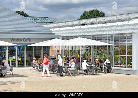 RHS Wisley Leute an neuen, modernen Cafe Gebäude Sonnenschirm Schatten & outdoor Tische neben Pflanzen shop Royal Horticultural Society Gärten Surrey England Großbritannien Stockfoto